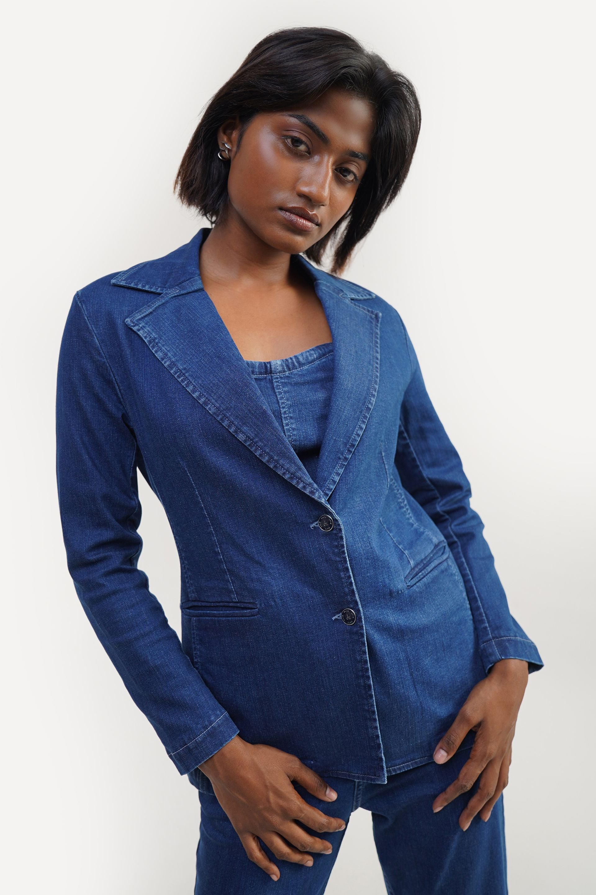 Mid blue women’s denim blazer in stretchable cotton fabric, fitted minimal style with front buttons and 2 flap pockets